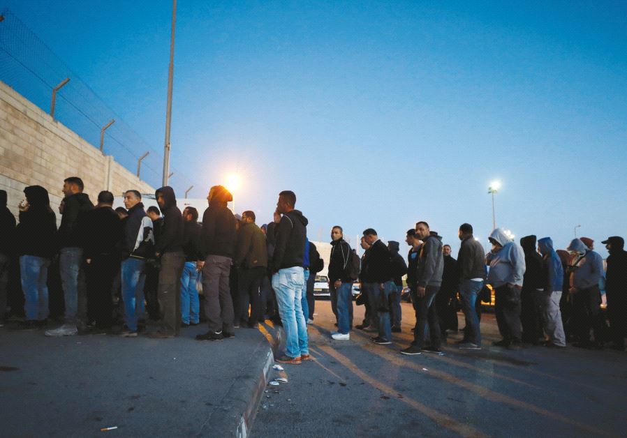 Palestinians working in Israel stand in line early in the morning as they wait to cross through Kalandiya checkpoint near Ramallah in April. Credit: Reuters